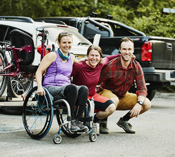 Portrait of smiling female wheelchair athlete and friends after mountain bike ride